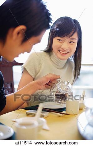 Young man pouring tea for young woman View Large Photo Image Picture - Young man pouring tea for young woman. Fotosearch