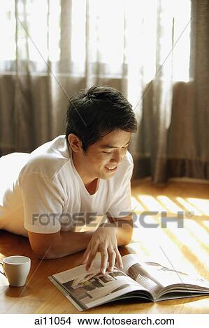 Young man reading magazine, smiling View Large Photo Image Picture - Young man reading magazine, smiling. Fotosearch