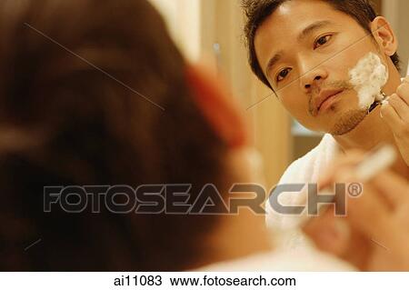 Young man shaving, looking in mirror, over the shoulder view View Large Photo Image Stock Image - Young man shaving, looking in mirror, over the shoulder view. Fotosearch