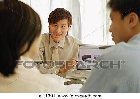 Young man showing laptop screen to couple in front of him View Large Photo Image Stock Image - Young man showing laptop screen to couple in front of him. Fotosearch