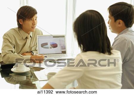 Young man showing laptop to couple in front of him View Large Photo Image Stock Image - Young man showing laptop to couple in front of him. Fotosearch