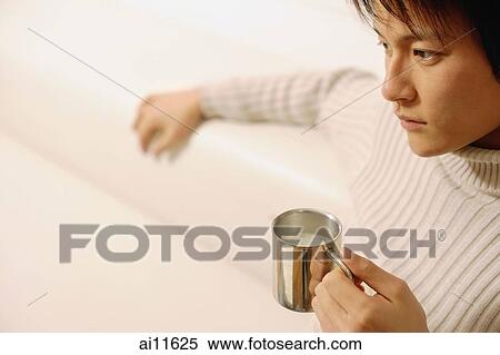 Young man sitting, holding coffee mug View Large Photo Image Stock Photography - Young man sitting, holding coffee mug. Fotosearch