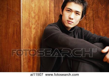 Young man sitting on floor, hugging knees View Large Photo Image Stock Photo - Young man sitting on floor, hugging knees. Fotosearch