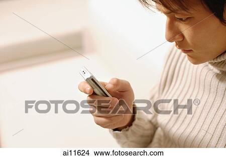 Young man sitting, using mobile phone View Large Photo Image Picture - Young man sitting, using mobile phone. Fotosearch
