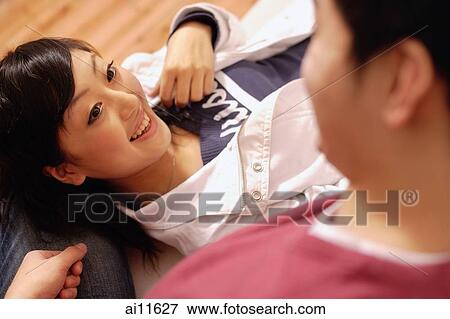 Young man sitting, young woman lying on his lap, looking up View Large Photo Image Stock Photo - Young man sitting, young woman lying on his lap, looking up. Fotosearch