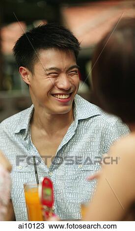 Young man smiling, woman in foreground View Large Photo Image Stock Image - Young man smiling, woman in foreground. Fotosearch
