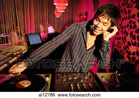Young man spinning at club, smiling View Large Photo Image Stock Photograph - Young man spinning at club, smiling. Fotosearch