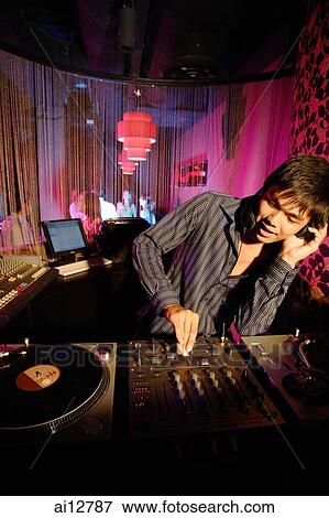 Young man spinning at club, using headphones View Large Photo Image Stock Photo - Young man spinning at club, using headphones. Fotosearch