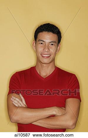 Young man standing, arms crossed, smiling at camera View Large Photo Image Stock Photo - Young man standing, arms crossed, smiling at camera. Fotosearch