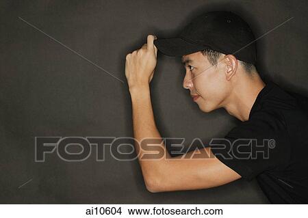 Young man touching cap, black background View Large Photo Image Picture - Young man touching cap, black background. Fotosearch