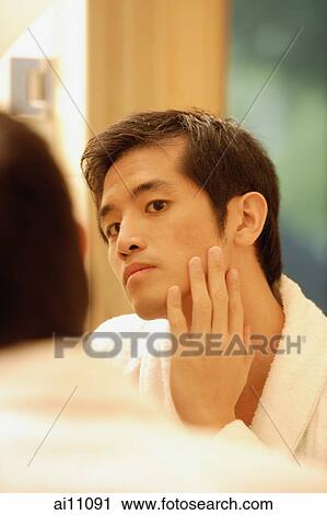 Young man touching his face, looking in mirror View Large Photo Image Stock Image - Young man touching his face, looking in mirror. Fotosearch