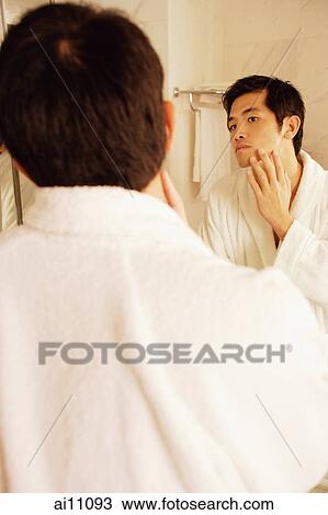 Young man touching his face, looking in mirror, rear view View Large Photo Image Stock Image - Young man touching his face, looking in mirror, rear view. Fotosearch