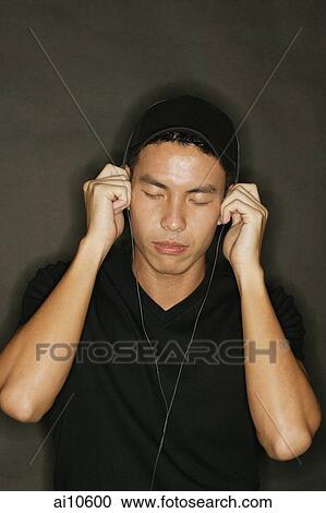 Young man using headphones, black background View Large Photo Image Stock Image - Young man using headphones, black background. Fotosearch