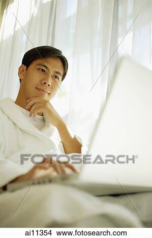 Young man using laptop, focus on the background View Large Photo Image Picture - Young man using laptop, focus on the background. Fotosearch