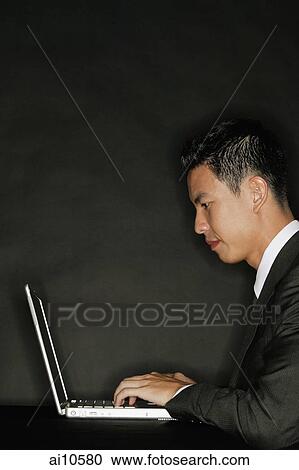 Young man using laptop, side view View Large Photo Image Stock Image - Young man using laptop, side view. Fotosearch