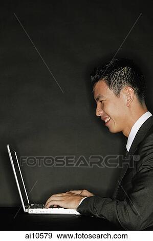 Young man using laptop, side view View Large Photo Image Stock Photo - Young man using laptop, side view. Fotosearch