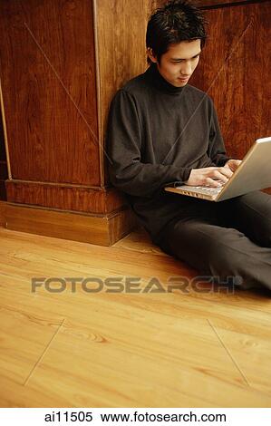 Young man using laptop, sitting on floor View Large Photo Image Stock Photography - Young man using laptop, sitting on floor. Fotosearch