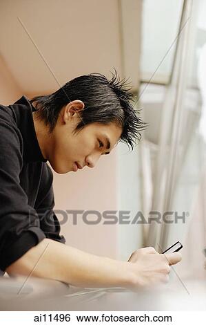 Young man using mobile phone, leaning on railing View Large Photo Image Stock Photograph - Young man using mobile phone, leaning on railing. Fotosearch