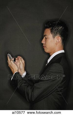 Young man using PDA, standing in profile View Large Photo Image Stock Photo - Young man using PDA, standing in profile. Fotosearch