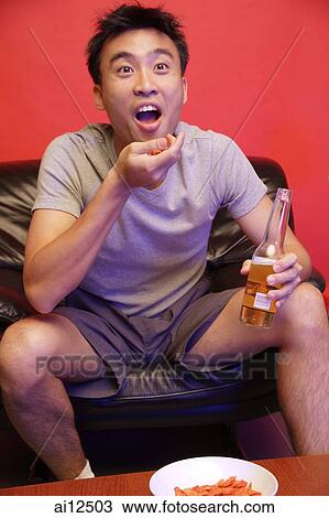 Stock Image - Young man watching TV. Fotosearch