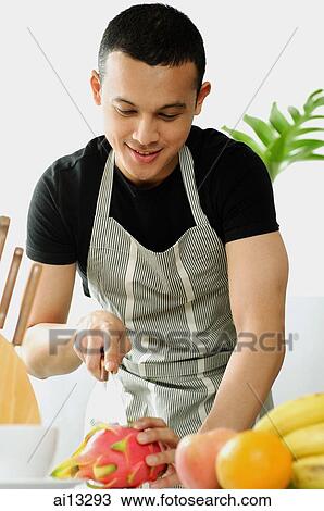 Young man wearing apron, cutting fruit View Large Photo Image Stock Image - Young man wearing apron, cutting fruit. Fotosearch
