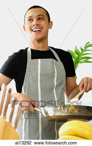 Young man wearing apron, holding saucepan, looking away View Large Photo Image Stock Image - Young man wearing apron, holding saucepan, looking away. Fotosearch