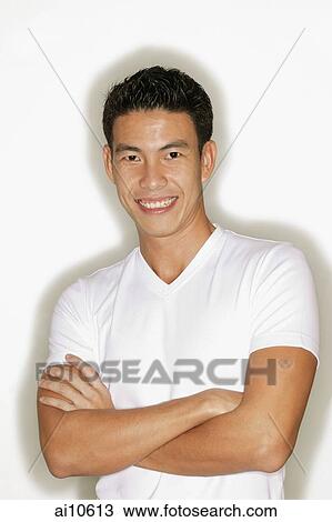 Young man with arms crossed, looking at camera View Large Photo Image Stock Image - Young man with arms crossed, looking at camera. Fotosearch
