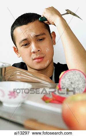 Young man with hand on head, looking at cut fruit, frustrated View Large Photo Image Stock Photo - Young man with hand on head, looking at cut fruit, frustrated. Fotosearch