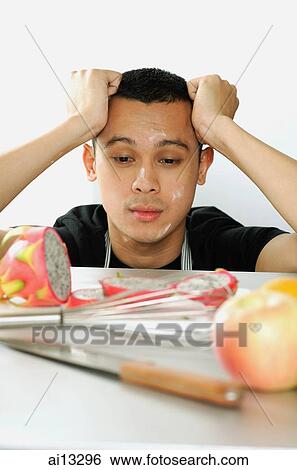 Young man with hand on head, looking at cut fruit View Large Photo Image Stock Photograph - Young man with hand on head, looking at cut fruit. Fotosearch