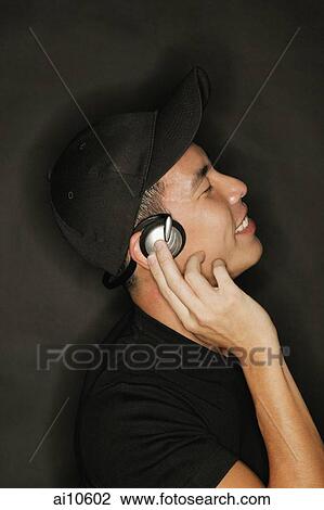 Stock Image - Young man with headphones, black background. Fotosearch