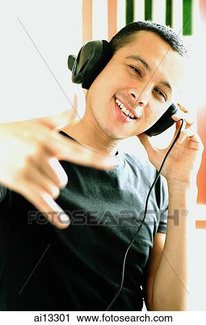Young man with headphones, making hand sign View Large Photo Image Stock Image - Young man with headphones, making hand sign. Fotosearch
