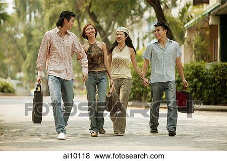 Young men and women walking hand in hand View Large Photo Image Stock Photo - Young men and women walking hand in hand. Fotosearch