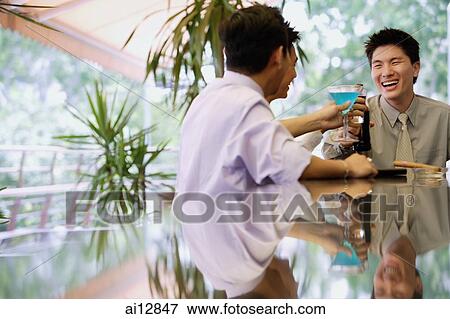 Young men at bar counter, raising drinks for a toast View Large Photo Image Stock Photo - Young men at bar counter, raising drinks for a toast. Fotosearch
