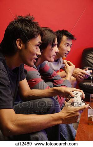 Young men holding video game controllers View Large Photo Image Stock Photo - Young men holding video game controllers. Fotosearch