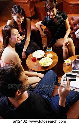 Stock Image - Young people at entertainment club, man holding out credit card for payment. Fotosearch