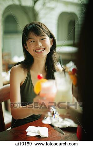 Stock Photo - Young woman and friends toasting with drinks.. Fotosearch