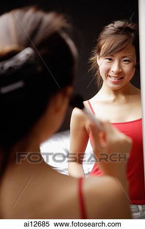 Young woman applying blusher, looking at mirror View Large Photo Image Stock Photography - Young woman applying blusher, looking at mirror. Fotosearch