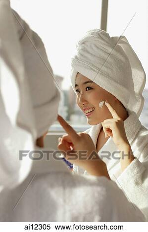 Young woman applying lotion on her face View Large Photo Image Stock Photography - Young woman applying lotion on her face. Fotosearch