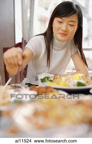Young woman at a Chinese restaurant, eating View Large Photo Image Picture - Young woman at a Chinese restaurant, eating. Fotosearch