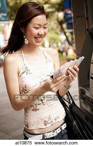 Young woman at an ATM machine, holding cash View Large Photo Image Stock Photography - Young woman at an ATM machine, holding cash. Fotosearch