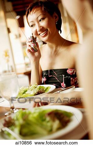 Young woman at restaurant, on the phone View Large Photo Image Stock Photograph - Young woman at restaurant, on the phone. Fotosearch