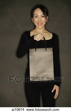Young woman carrying shopping bag, black background View Large Photo Image Picture - Young woman carrying shopping bag, black background. Fotosearch