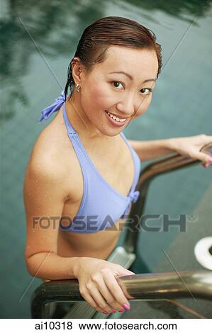 Stock Photo - Young woman climbing out of swimming pool.. Fotosearch