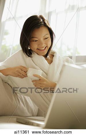 Young woman drinking coffee, laptop open in front of her View Large Photo Image Stock Image - Young woman drinking coffee, laptop open in front of her. Fotosearch