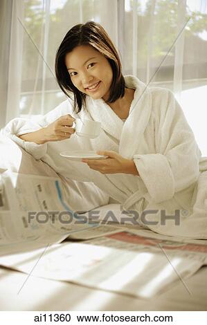Young woman drinking coffee, newspaper open in front of her View Large Photo Image Stock Image - Young woman drinking coffee, newspaper open in front of her. Fotosearch