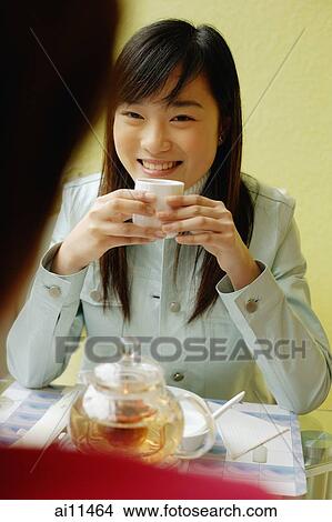 Young woman drinking tea, facing another person View Large Photo Image Picture - Young woman drinking tea, facing another person. Fotosearch