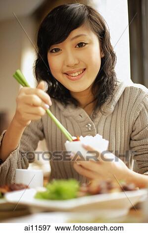 Young woman eating at a restaurant, looking at camera View Large Photo Image Stock Photo - Young woman eating at a restaurant, looking at camera. Fotosearch