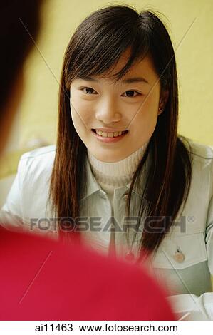 Young woman facing another person, smiling View Large Photo Image Stock Image - Young woman facing another person, smiling. Fotosearch