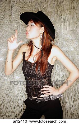 Stock Image - Young woman, hands on hip, wearing cowboy hat. Fotosearch