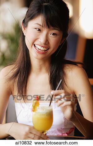 Young woman holding a drink, looking at camera View Large Photo Image Stock Image - Young woman holding a drink, looking at camera. Fotosearch